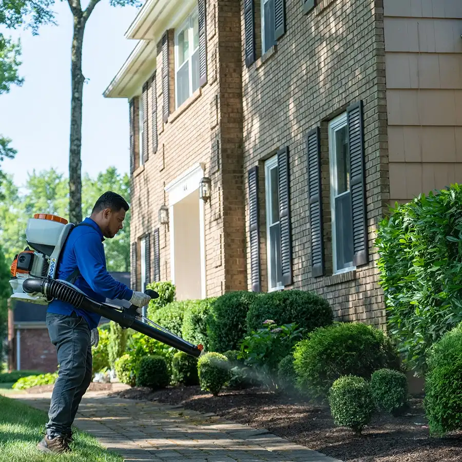 Lawn care technician applying a pest control treatment to a North Jersey lawn to protect turf from damaging insects